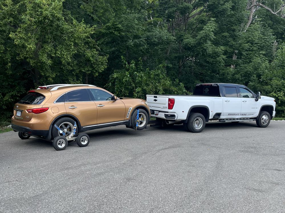 Bishopgate truck towing an SUV from a wooded driveway